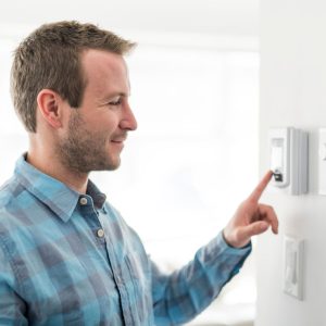 smiling man adjusting thermostat